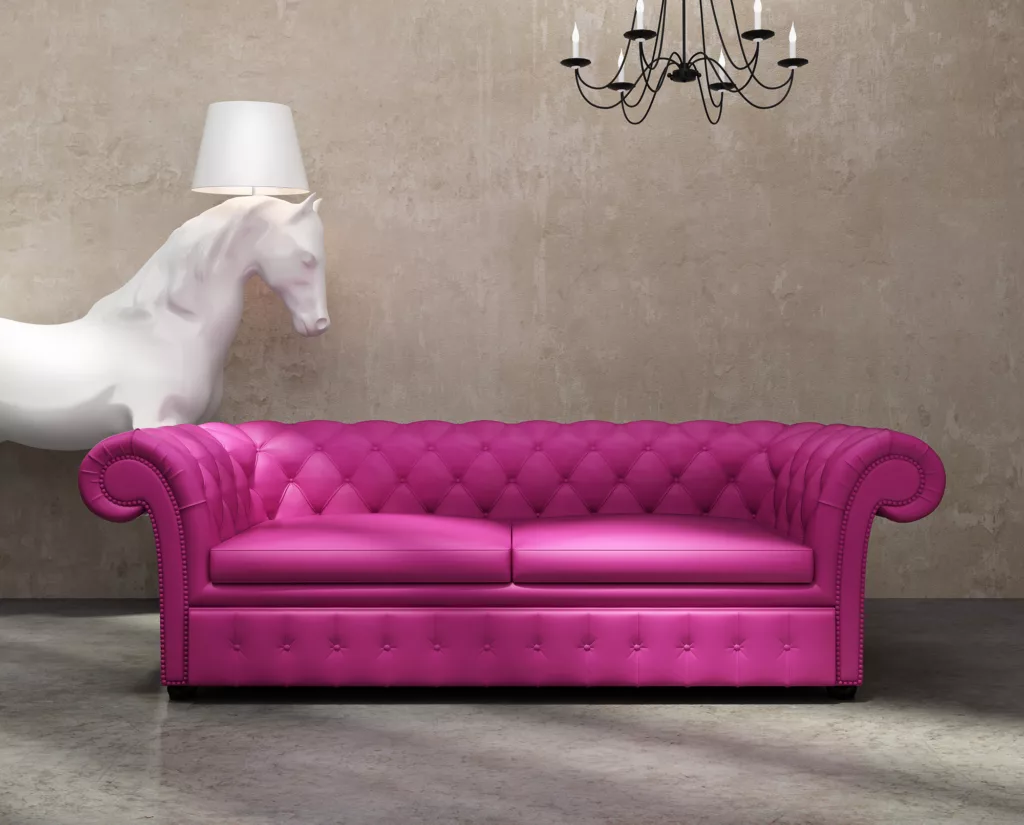 Pinkes Sofa steht vor einer Wand, im HIntergrund ein weißes Dekopferd mit Lampfe -dekoratives Bild für Marke auf derCouch - BrandShrink - Kontakt